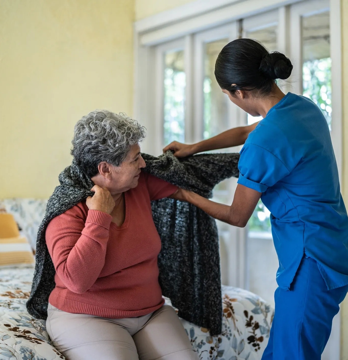 Caregiver helping elderly woman in assisted living